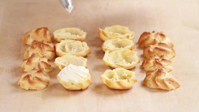 Profiteroles being filled with cream