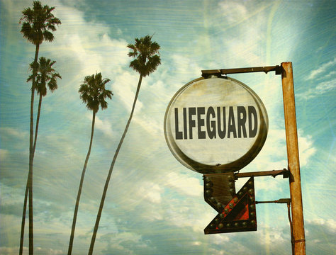 aged and worn vintage photo of lifeguard sign with palm trees