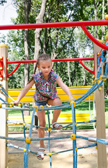 Smiling little girl playing on playground equipment