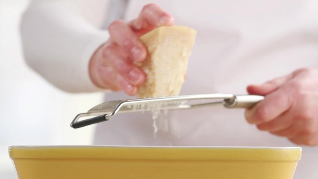 Lasagne being sprinkled with freshly grated Parmesan cheese