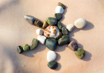 Female body, sun symbol made of white pebble stones