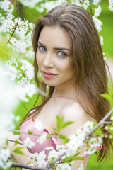 Fototapeta premium Portrait of beautiful young brunette woman in spring blossom