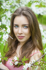 Fototapeta premium Portrait of beautiful young brunette woman in spring blossom