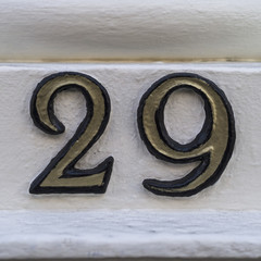 The number twenty nine in gold lettering on a white wooden background