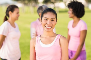 Smiling woman wearing pink for breast cancer in front of friends