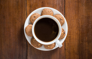 Coffee cup and tasty cookie on wooden background, top view