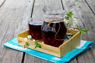 Compote of cherries in a jar on a wooden background