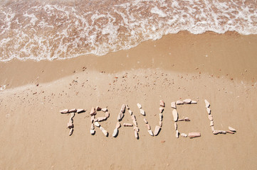 travel written on sandy beach near sea