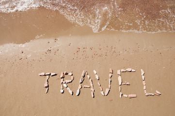 travel written on sandy beach near sea