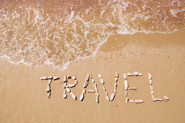 travel written on sandy beach near sea