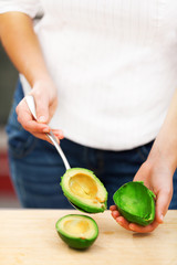 Young woman peeling avocado
