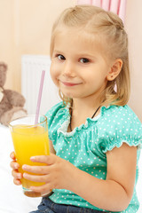 Happy little girl with glass of orange juice