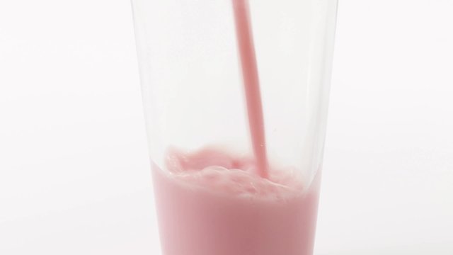 Pouring strawberry milk into a glass