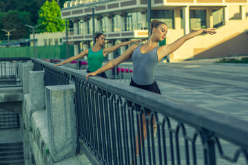 Two young beautiful twin sister dancing ballet in the city with ballet costume. urban sync...
