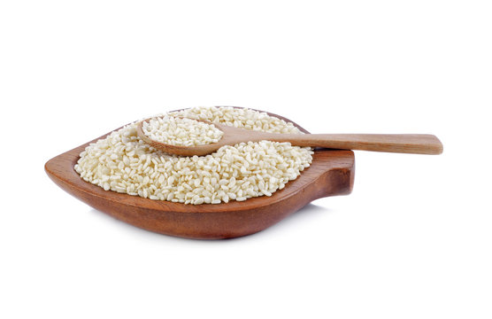 Heap of white Sesame (close-up shot) wooden spoon on background