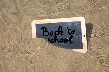 Back to school written on a board in the sand