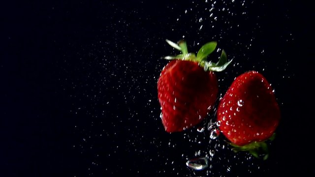 Strawberries floating in water (black background)