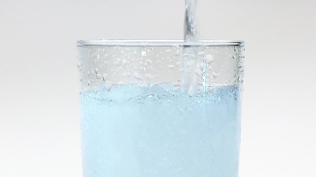 Pouring mineral water into a glass of crushed ice (close-up)