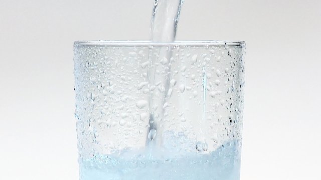 Pouring water into a glass of crushed ice (close-up)