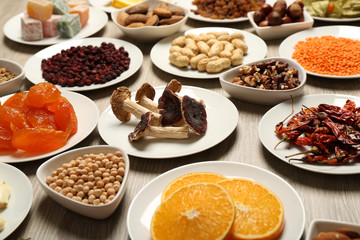 Different products on saucers on wooden table, closeup