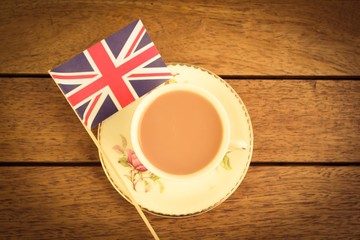 A cup of tea and a union jack on a wooden table