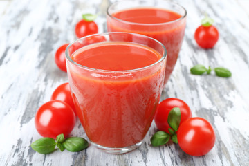 Glasses of tomato juice with vegetables on wooden background