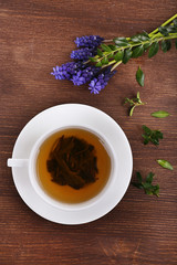 Cup of herbal tea with flowers on wooden table, top view