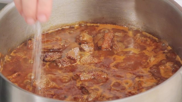 Seasoning beef goulash with salt and pepper