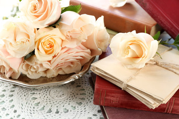 Fresh roses with old book and letters on color wooden table background. Vintage concept