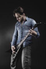 Handsome guitarist playing his electric guitar on black backgrou