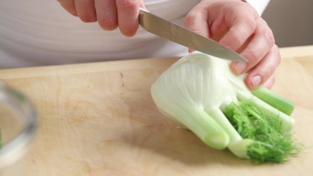 Halving a bulb of fennel and cutting out the core in a wedge