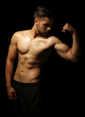 Fototapeta premium Muscle young man on dark background