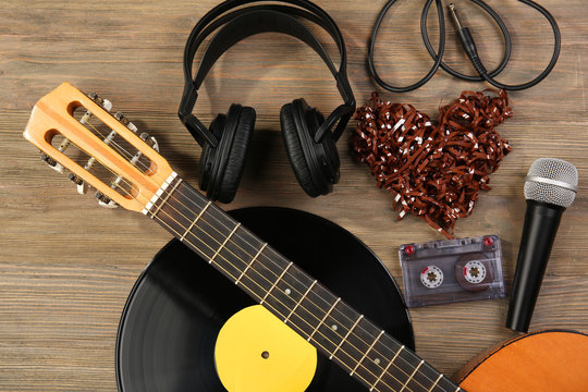 Music recording scene with classical guitar, vinyl record, microphone, cassette and headphones on wooden background