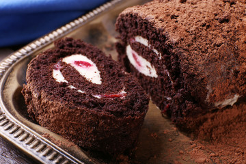 Chocolate roll with cream and berries on table close up