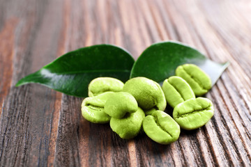 Green coffee beans with leaves on wooden background