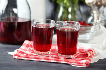 Sweet homemade cherry juice on table, on color background