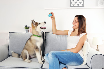 Woman playing with malamute dog on sofa in room
