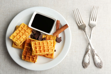 Sweet homemade waffles on plate, on light background