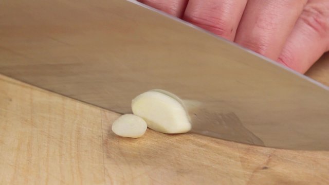 A garlic clove being finely chopped