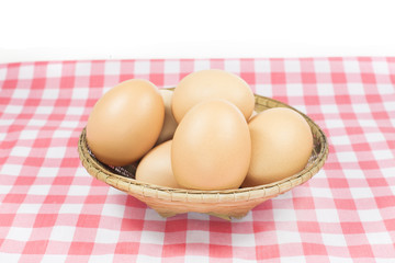Eggs in basket on pink color plaid on white background