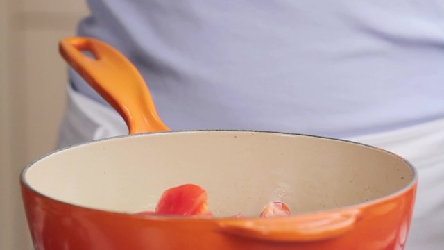 Chopped courgette being added to a pan and seasoned salt