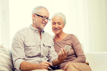 happy senior couple with smartphone at home