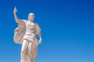 A statue of St Elijah the prophet holding a knife on a blue sky