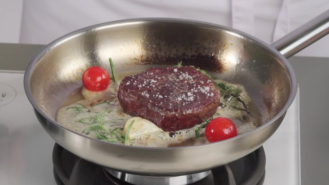 A fillet steak being season and aromatised with herbs, garlic and tomatoes