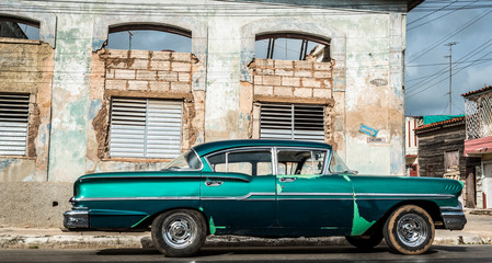 Auf der Strasse parkender grüner Oldtimer vor einem Gebäude in Varadero Cuba