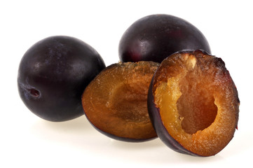 Prunes entières à côté d'une prune coupée en deux
