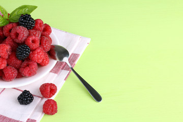 raspberries and blackberries on a plate light green background