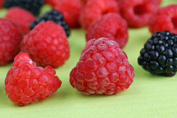raspberries and blackberries on a light green background