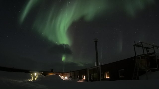 Winter in Arctic. Starry sky in the polar night. Northern Lights over polar station.