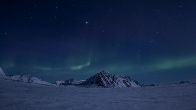 Winter in Arctic. Starry sky in the polar night. Northern Lights over glacier.